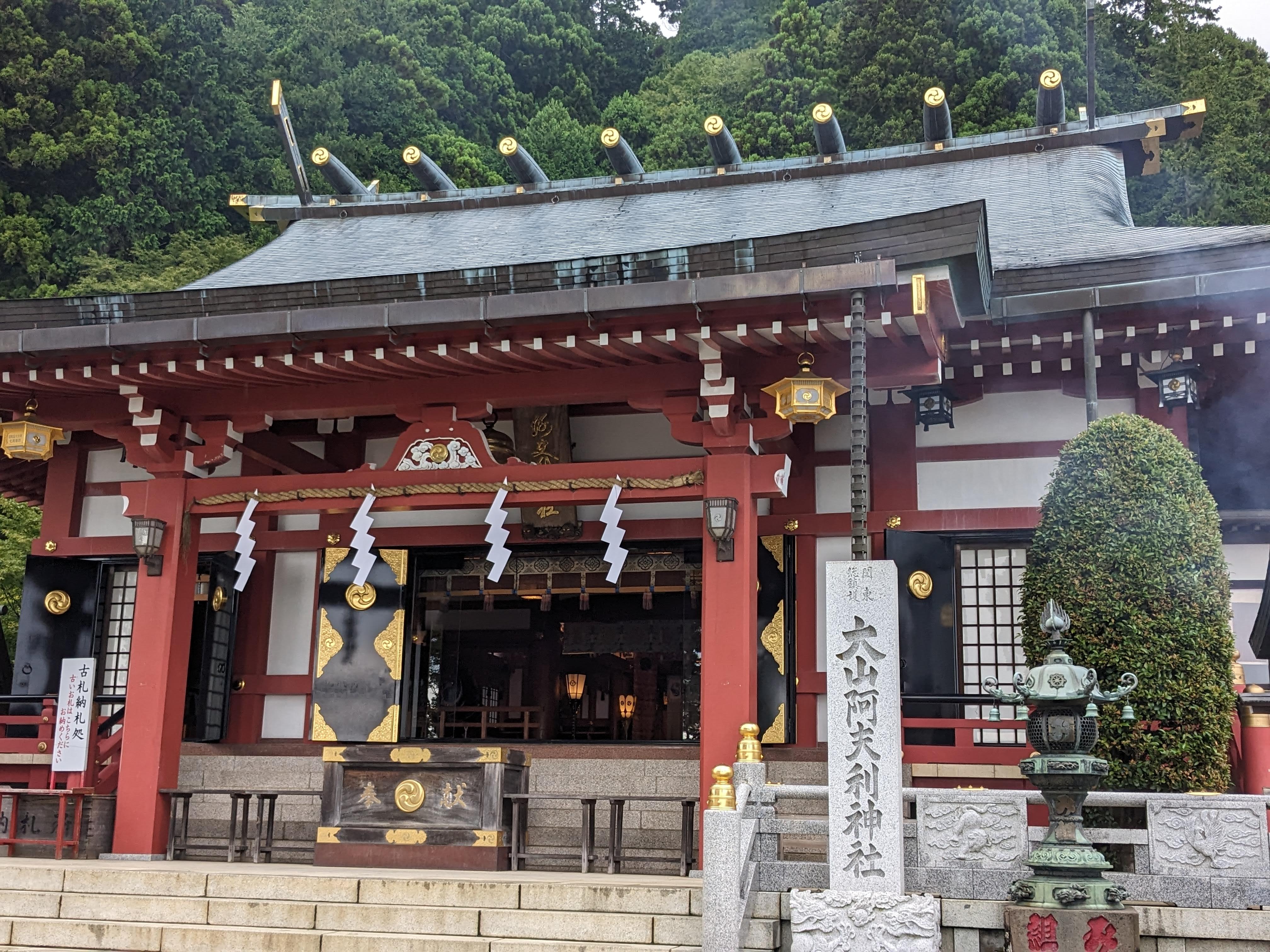 朱塗りの装飾が鮮やかな大山阿夫利神社下社の拝殿と石碑